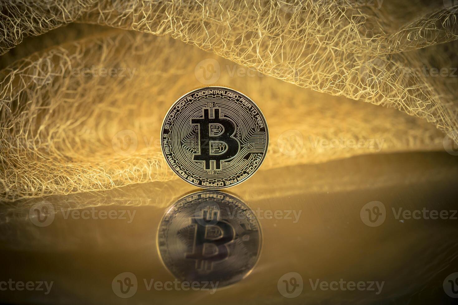 Bitcoin with mirror image in front of a tile made of gold threads photo