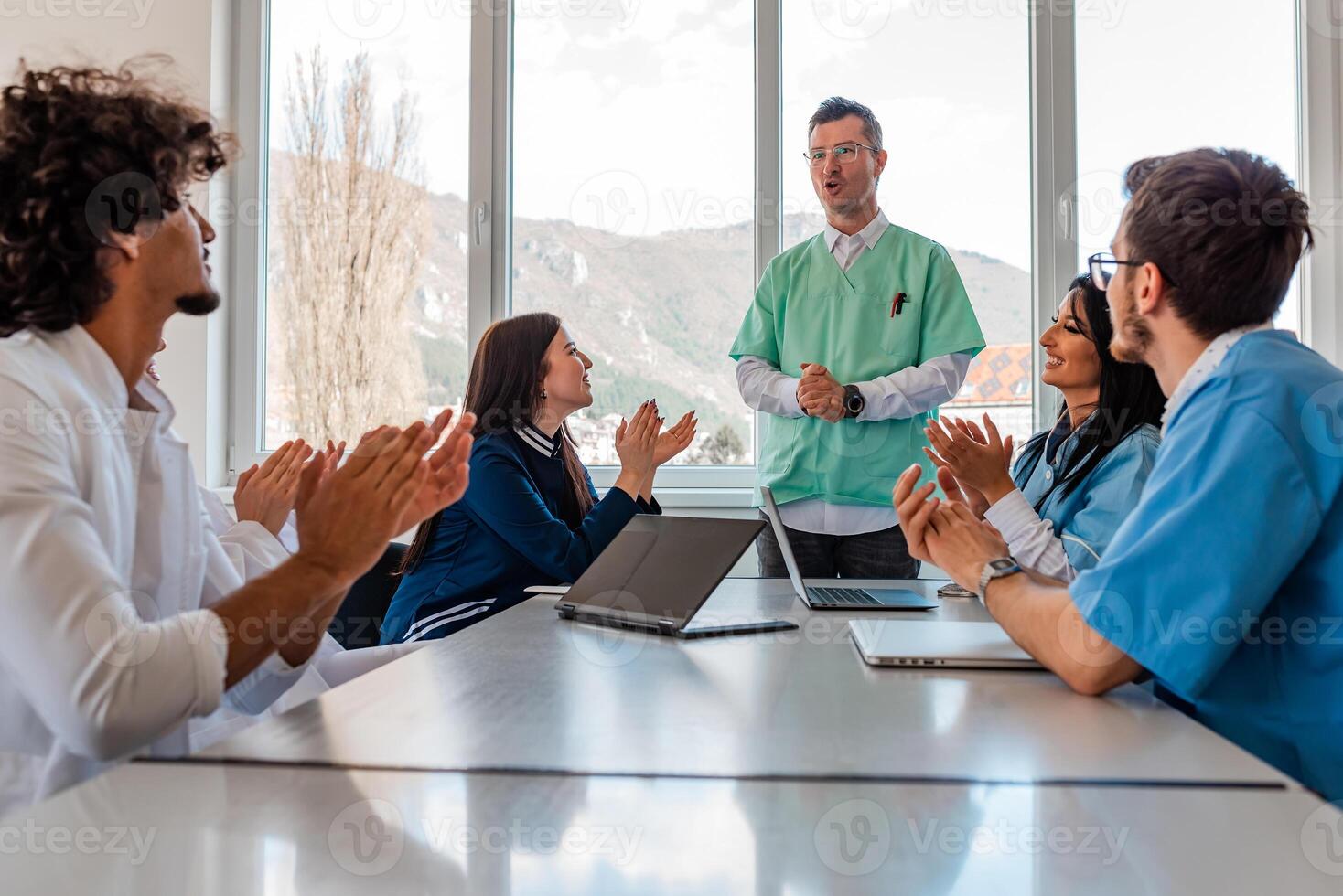 A medical team of doctors supports with applause and candid smiles in celebration at the meeting in the office concept of teamwork success leadership. photo