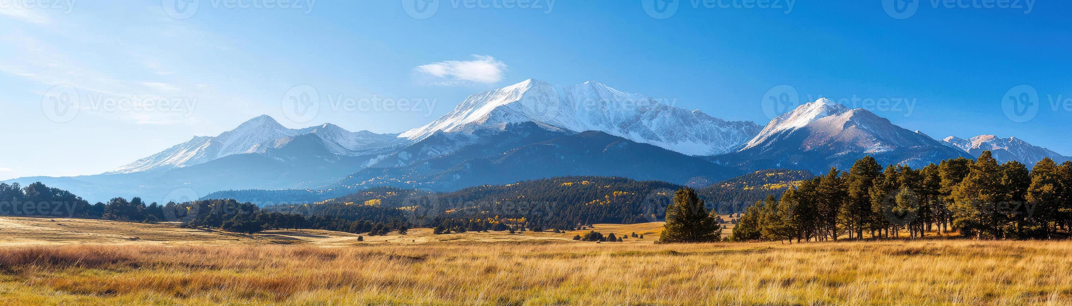Majestic mountain range with lush fields and clear blue sky photo