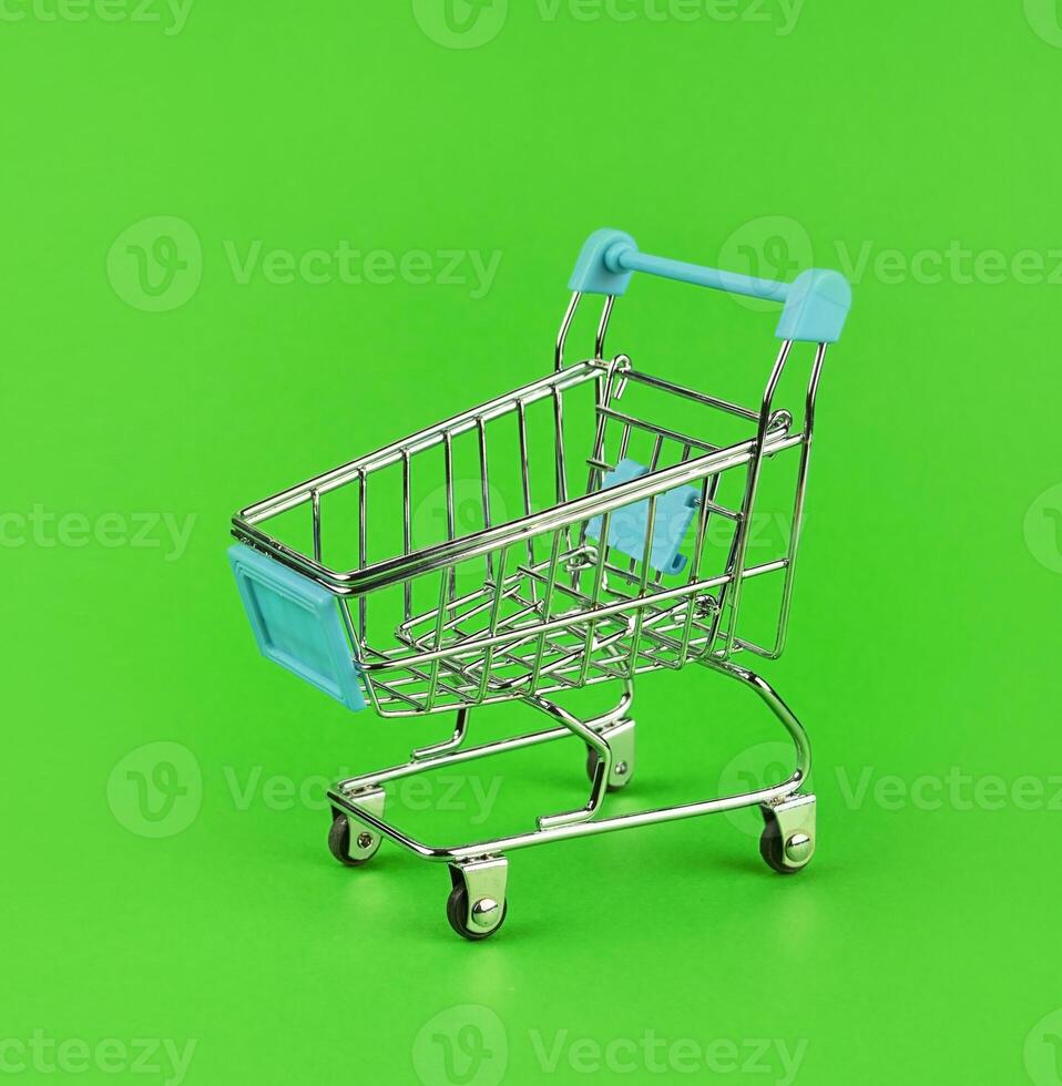 Shopping cart on a green background close-up. photo