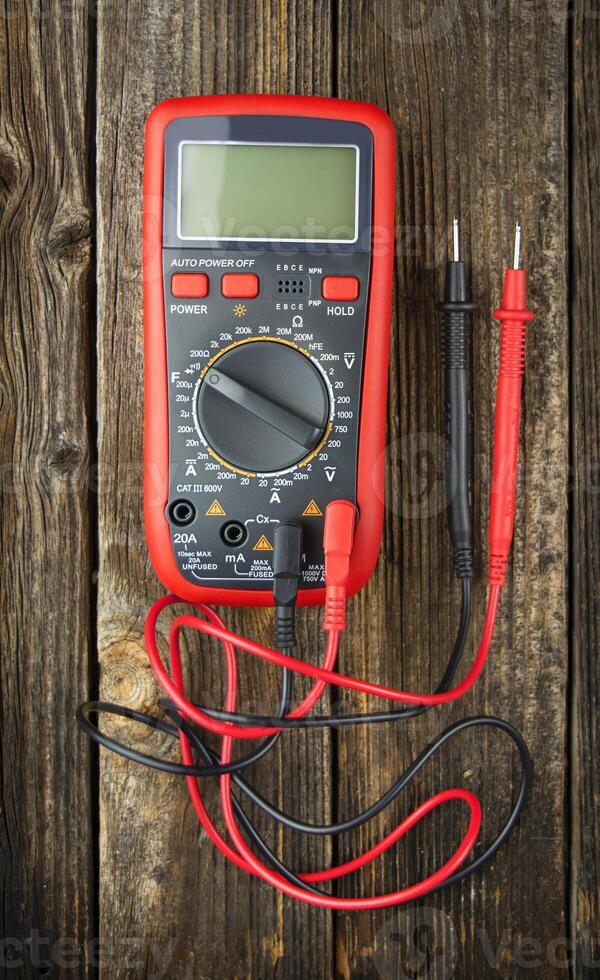 Digital multimeter on a wooden table. A device for measuring electrical quantities. View from above. photo