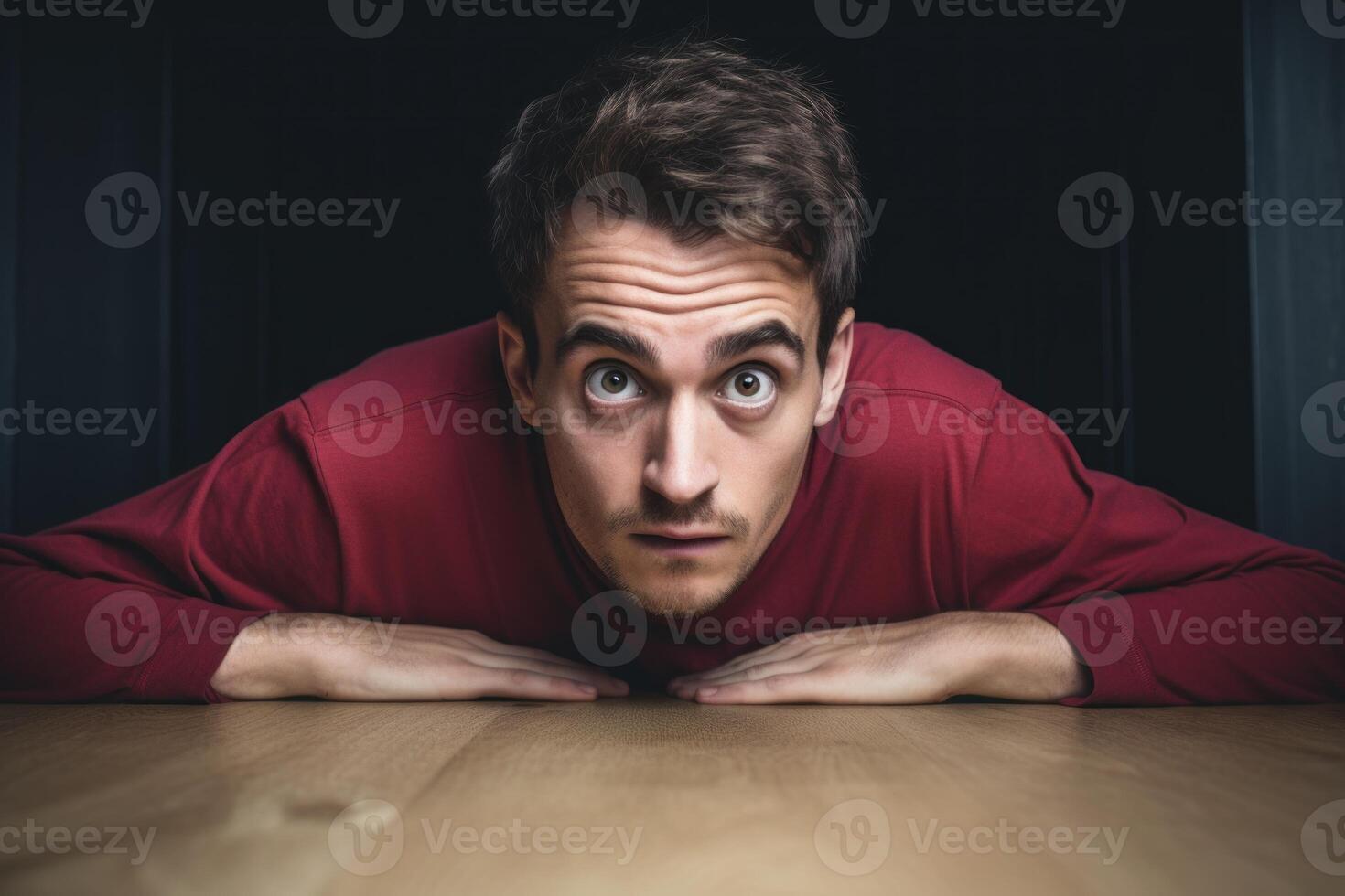 Curious man looking over table with amazement and surprise photo