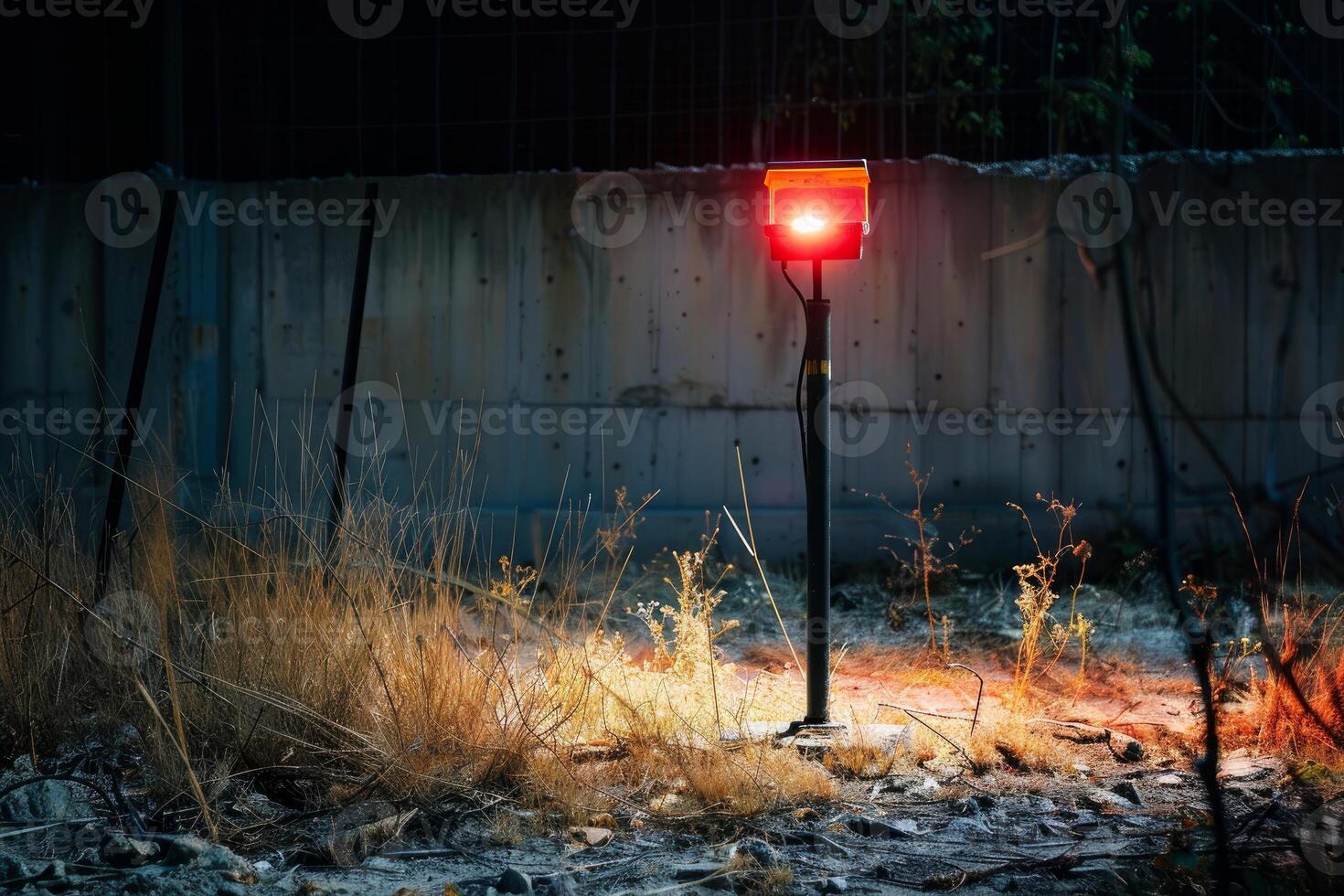 Red light shining on dry grass at night in deserted industrial area photo
