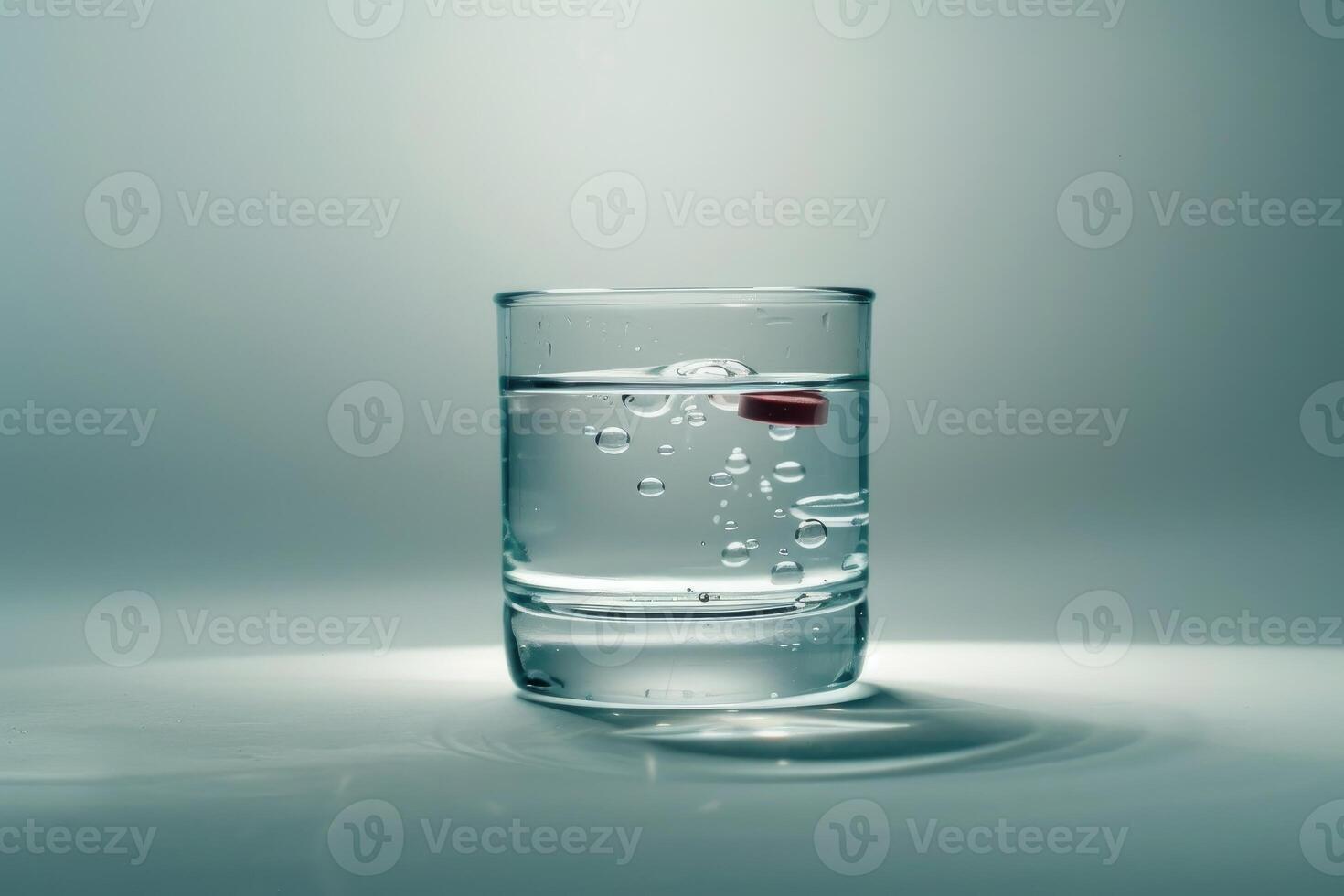 Red pill dissolving in a glass of water on gradient background photo
