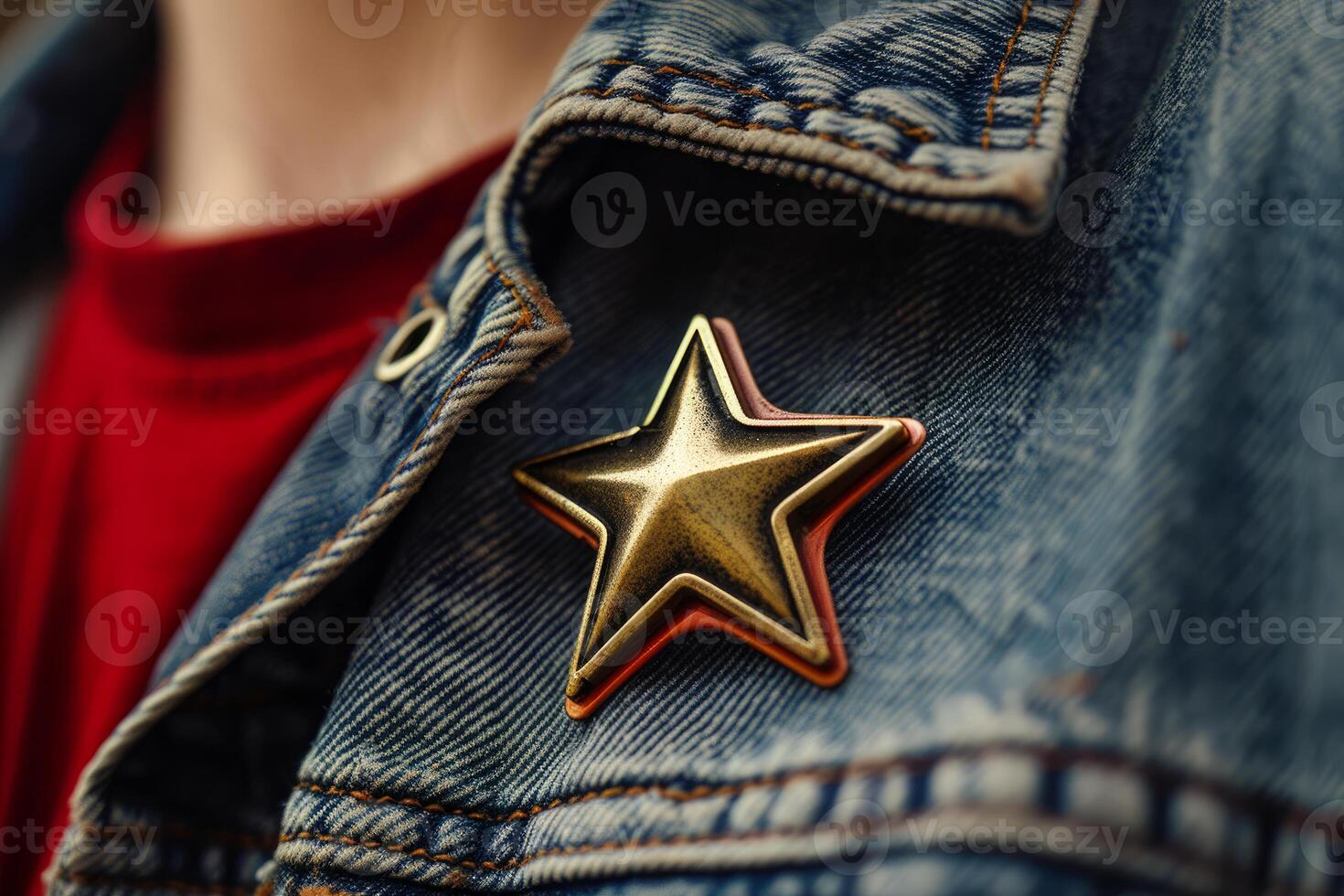 Person wearing denim jacket with red shirt showing five pointed star pin photo