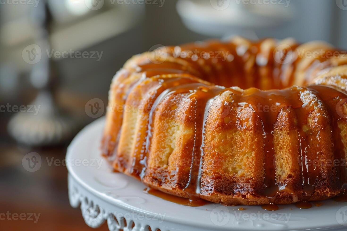 Round cake with caramel topping drizzled on top sitting on white pedestal photo
