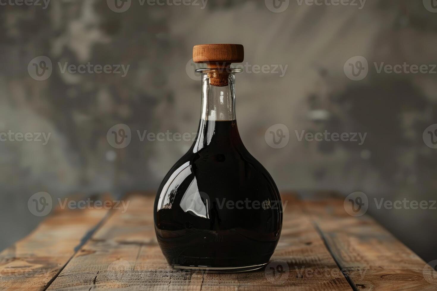 Glass bottle full of alcohol standing on wooden surface photo