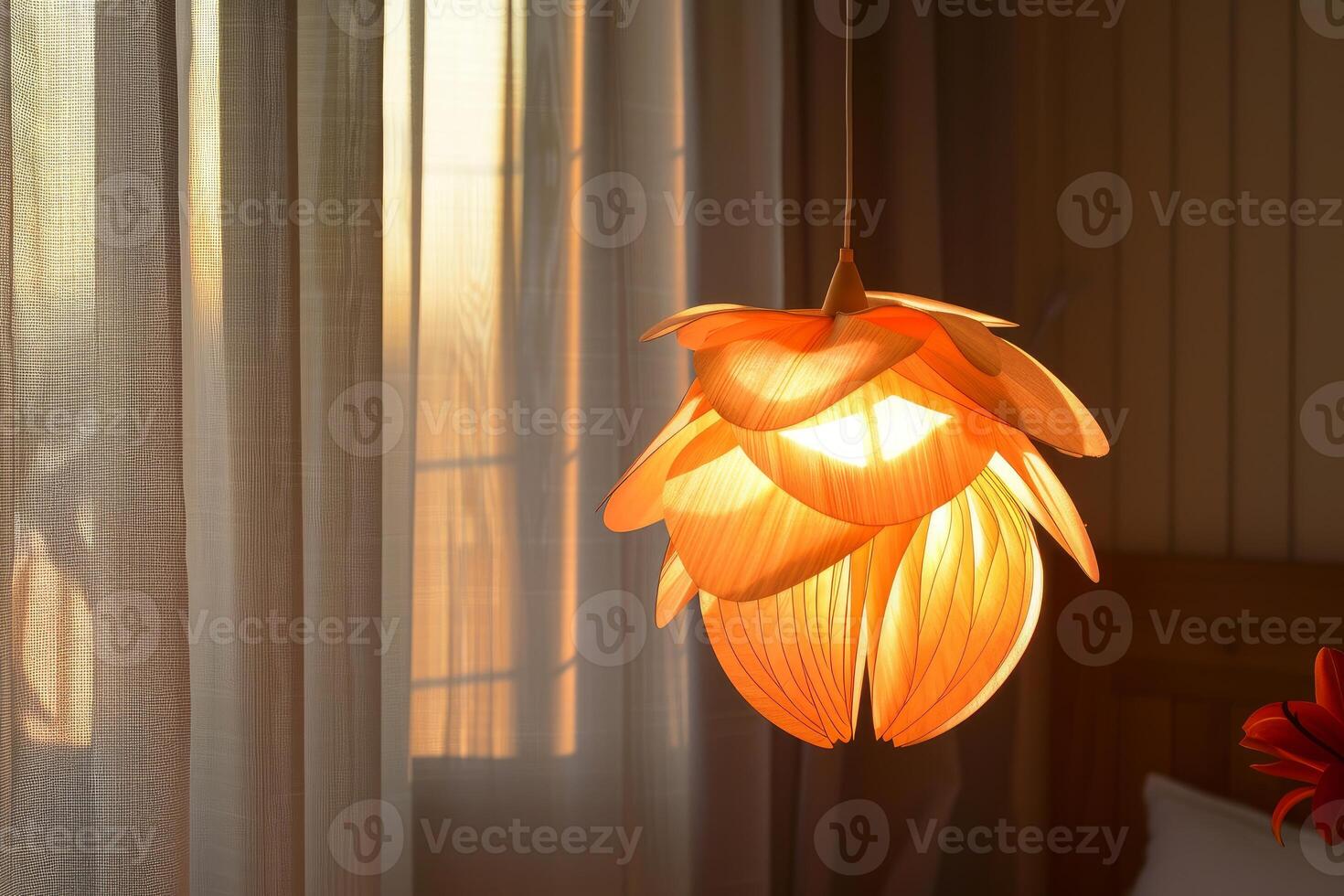 Modern flower shaped lamp hanging from ceiling illuminating room with sunset light shining through window photo