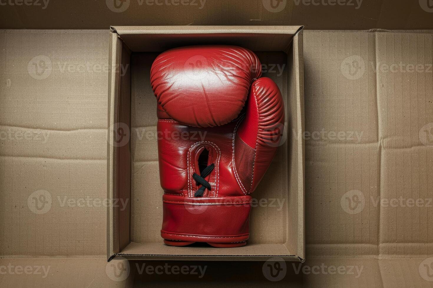 Red boxing glove resting inside open cardboard box photo