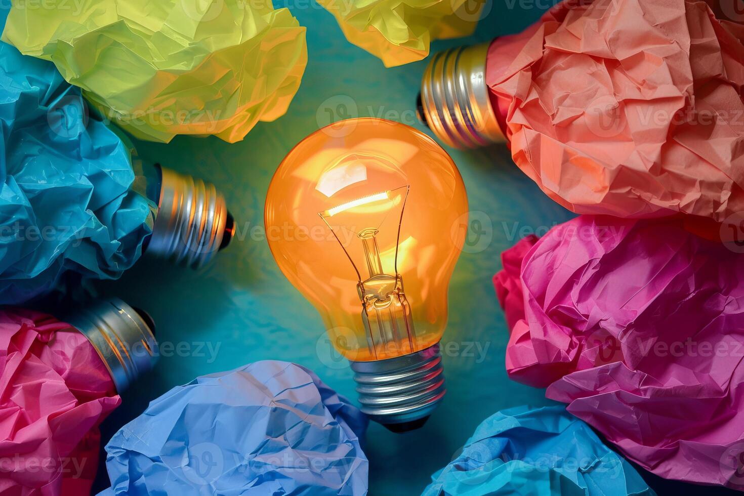 Glowing light bulb surrounded by crumpled colorful paper representing ideas photo