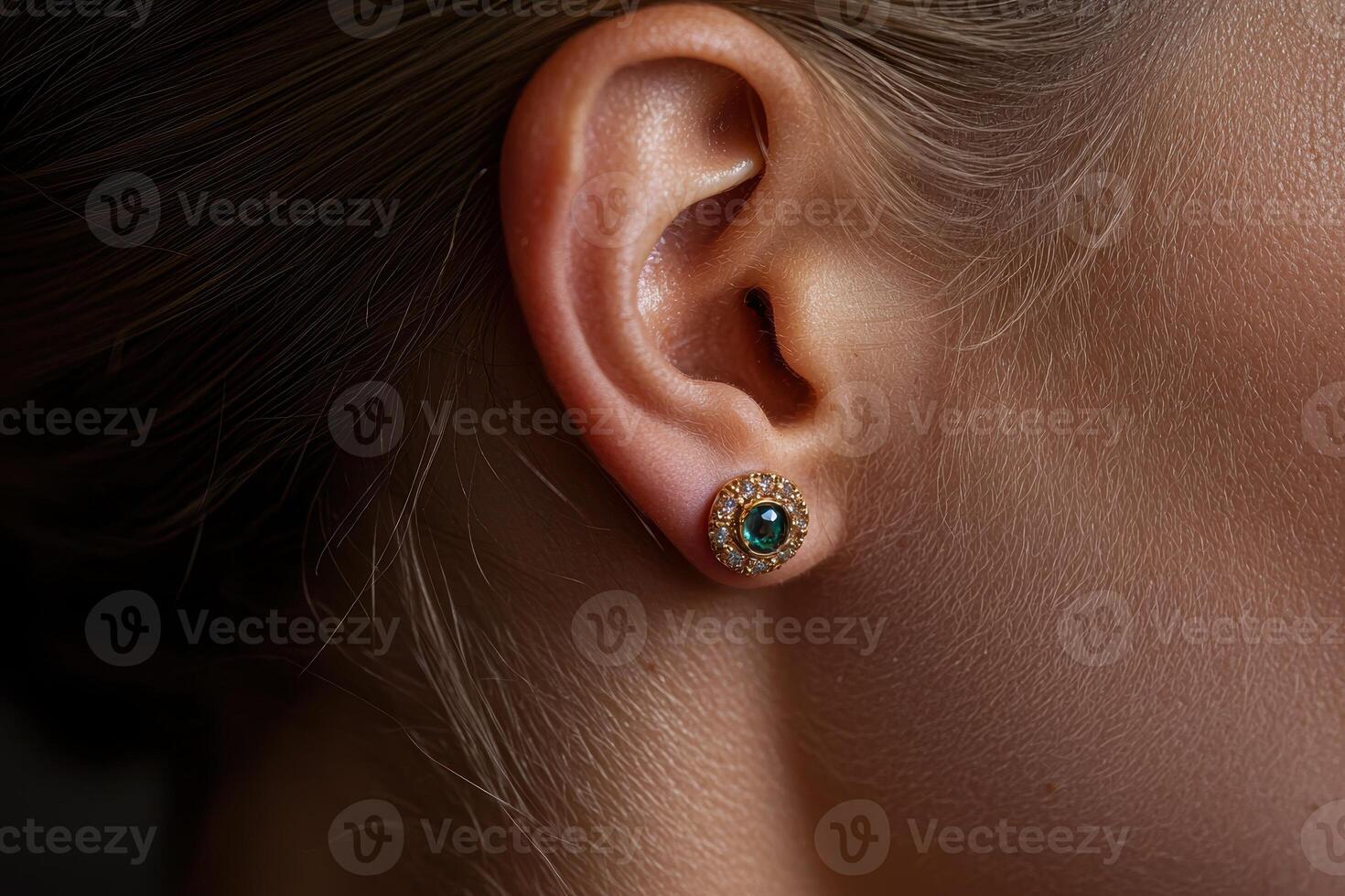 Close up of a womans ear with emerald and diamond earrings photo
