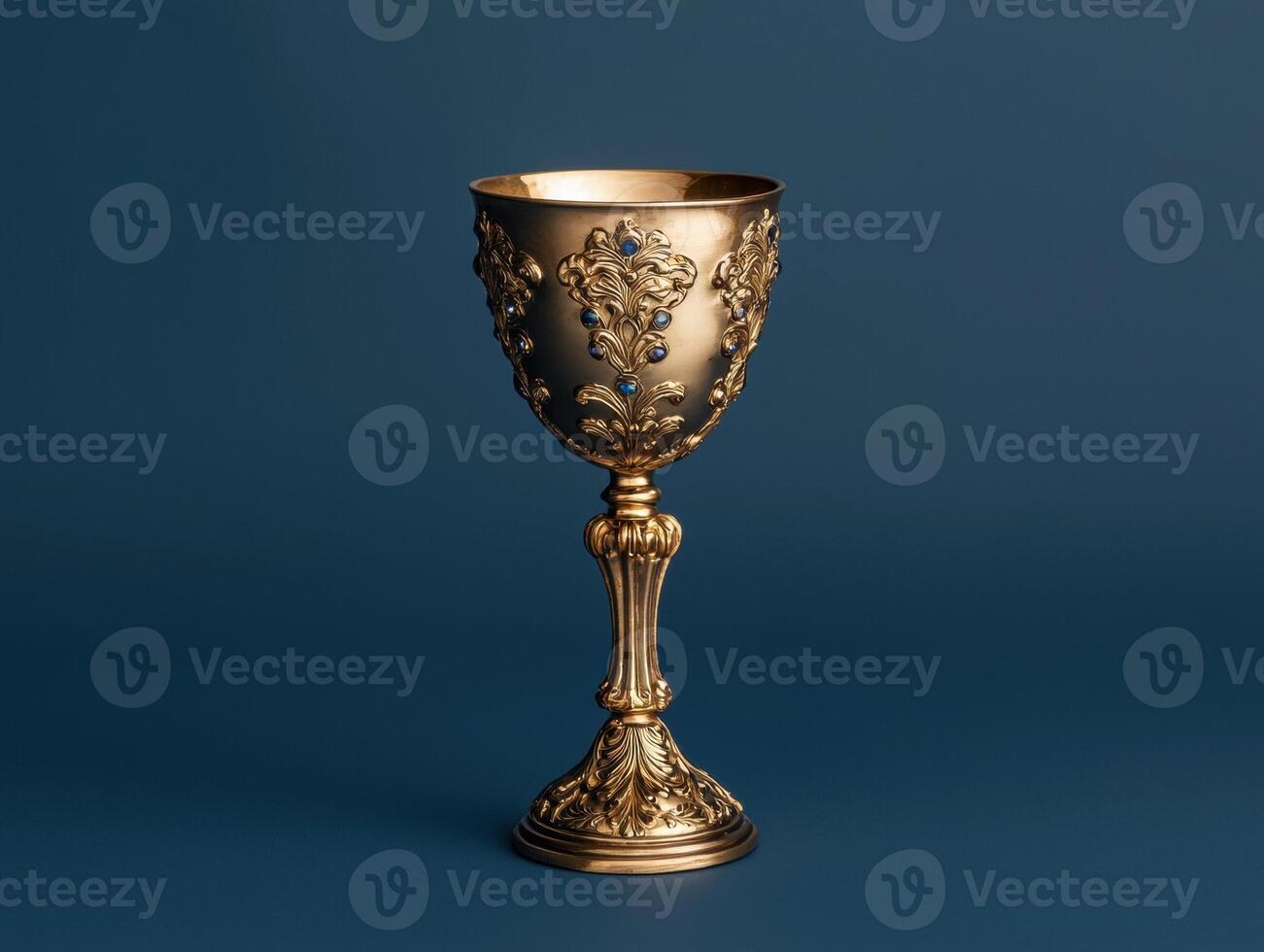 Ornate golden chalice with blue gems on dark background photo