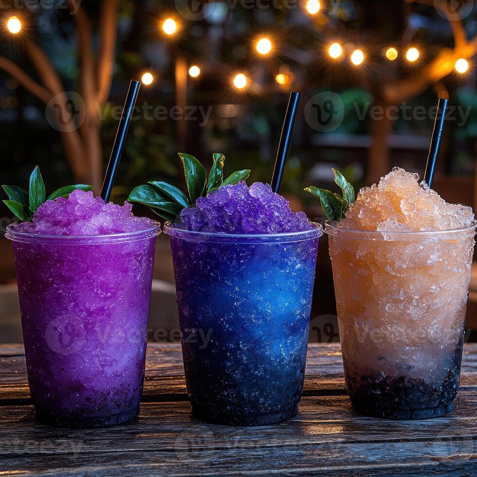 Three colorful shaved ice drinks on a wooden table at night photo