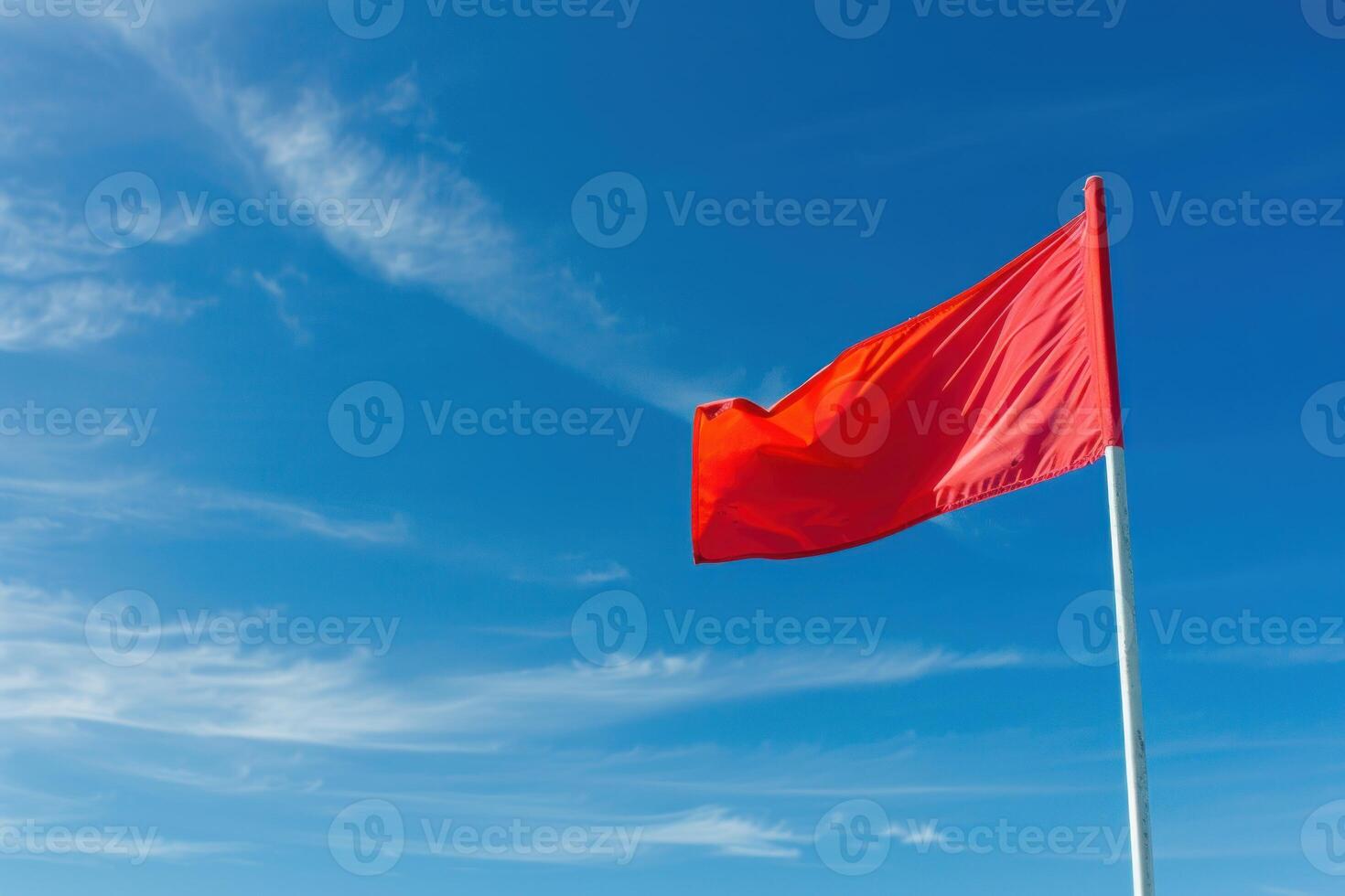 Red flag waving in the wind against blue sky with light clouds photo