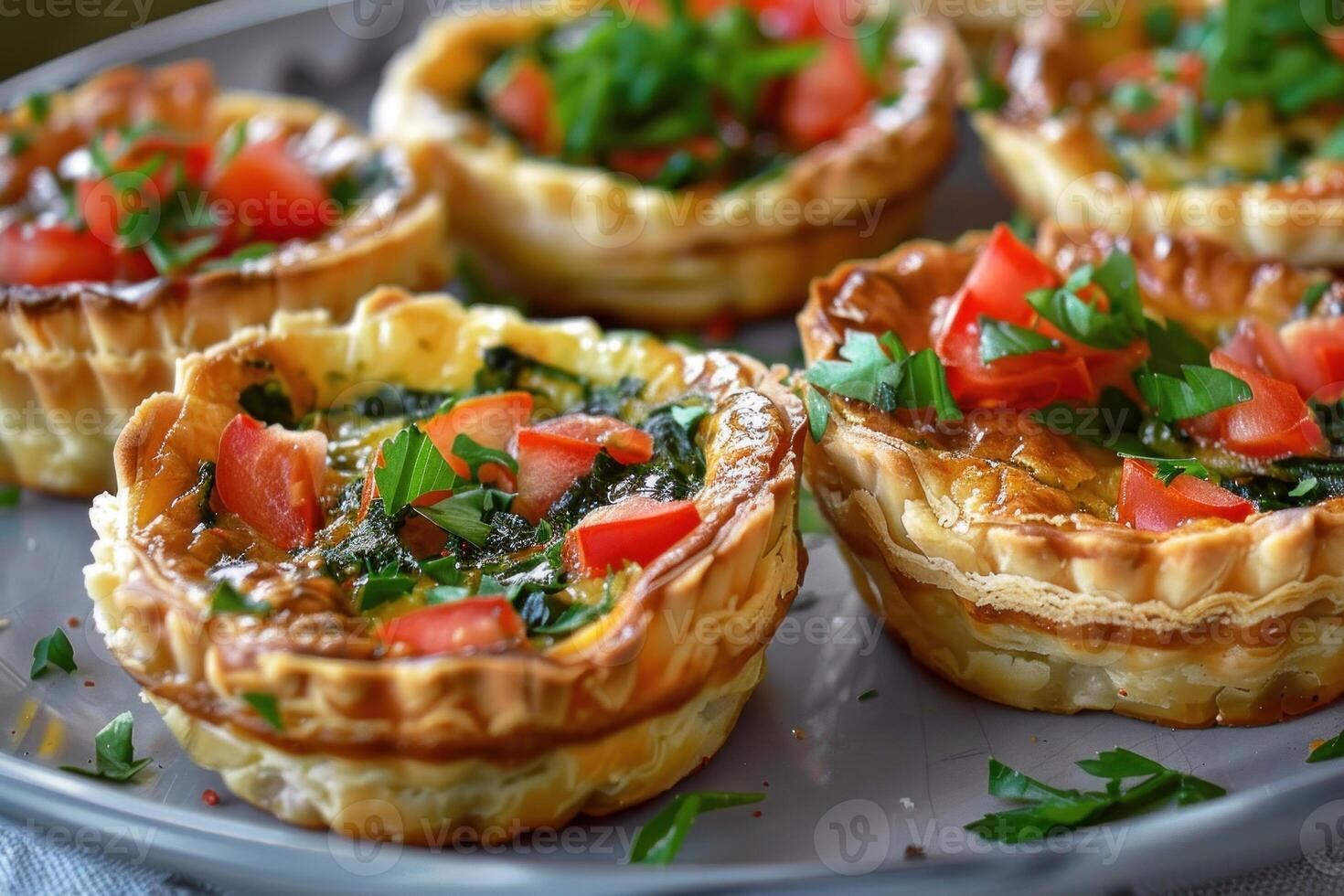 Delicious homemade mini quiches with spinach, tomatoes, and fresh herbs baking on a plate photo