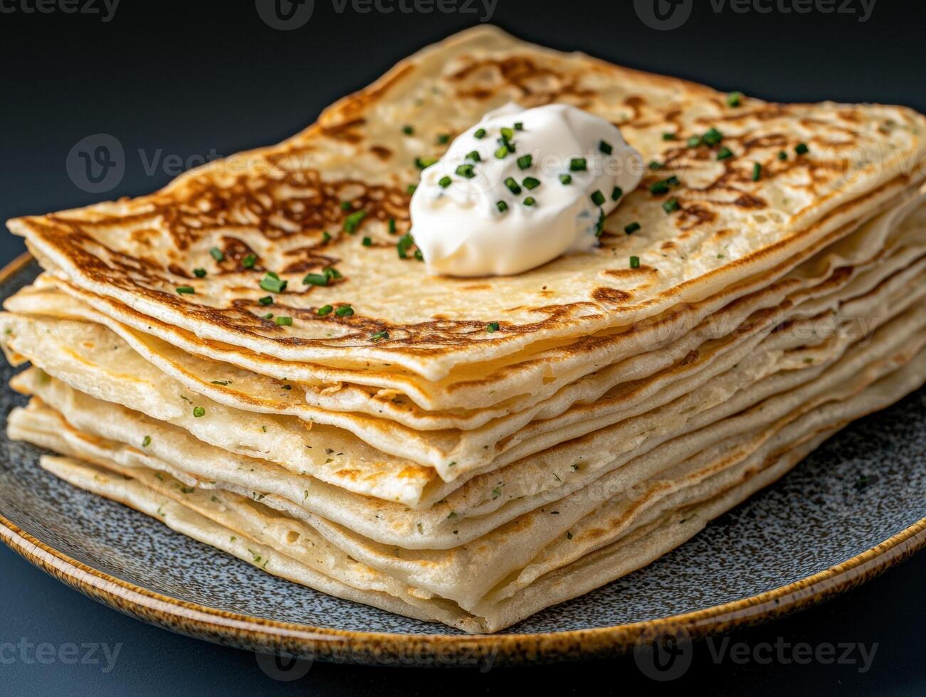 Stack of thin pancakes with sour cream and chives photo
