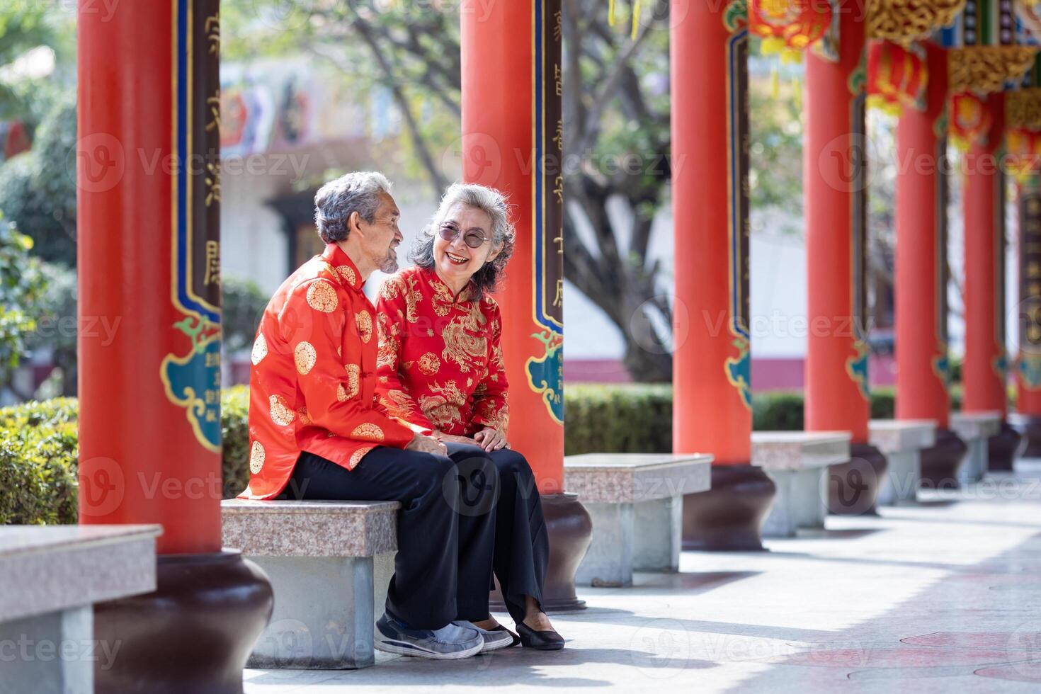 Asian marriage senior couple in cheongsam qipao dress is talking to each other inside the temple during Chinese new year for family and relative gathering in hometown photo