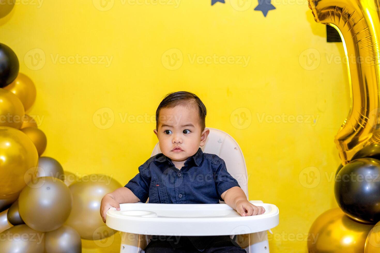 Cute adorable baby boy sitting in his high chair. Cute toddler Biting His Finger in a Sweet Pose photo