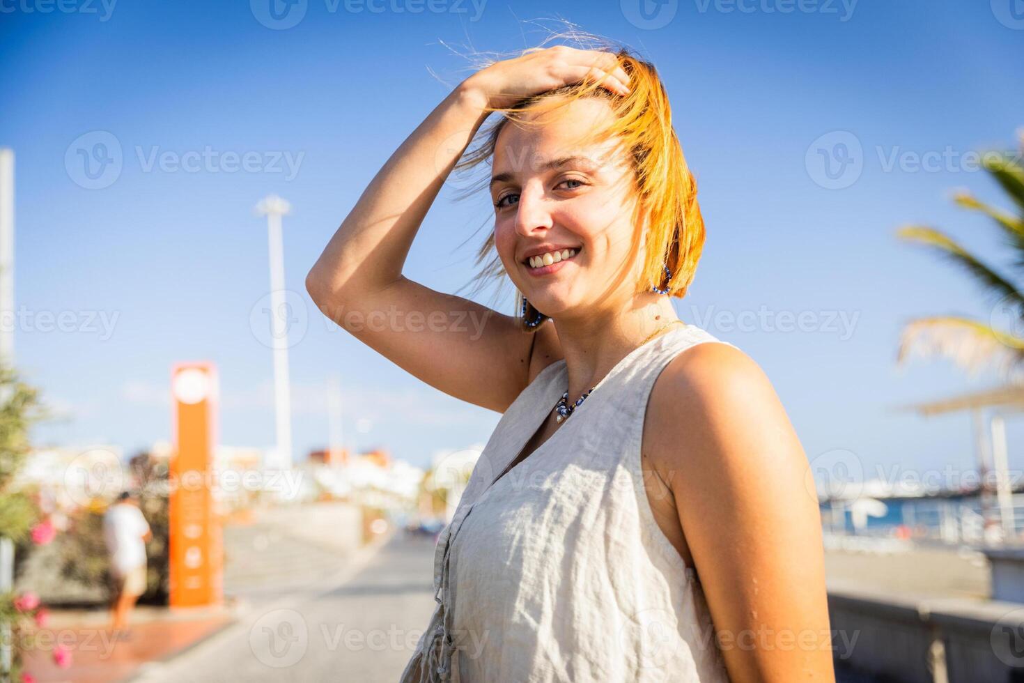 A woman with red hair is smiling and posing for a picture, sunny day photo