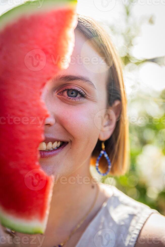 A woman is holding a watermelon slice in front of her face, summer vibes photo