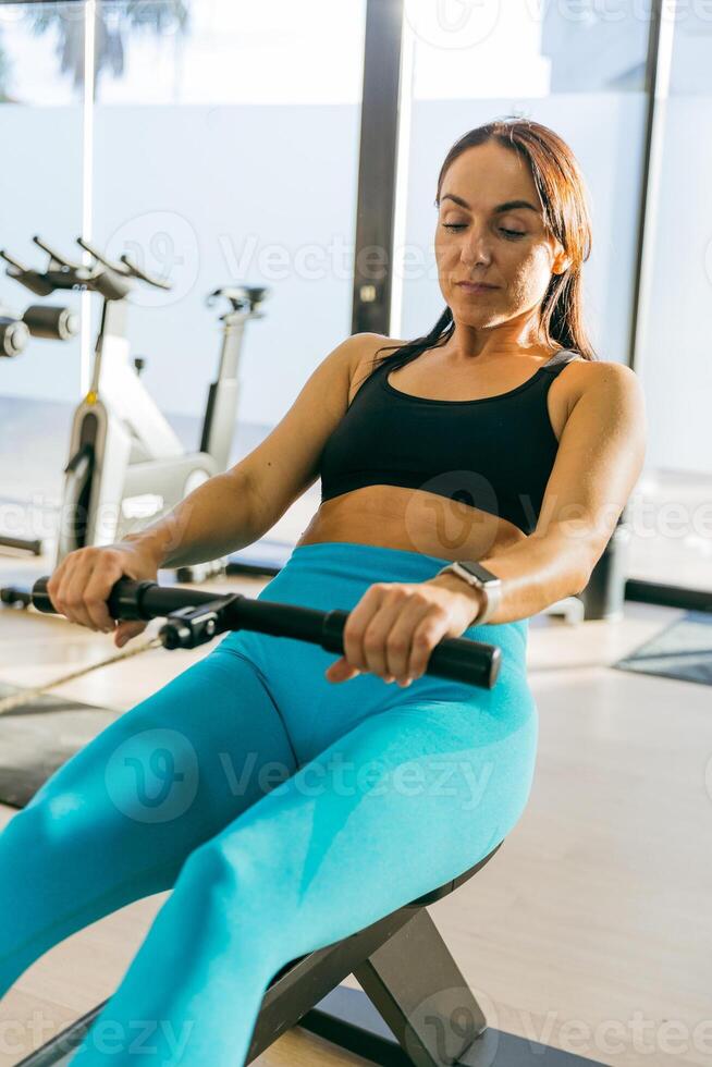 A woman is rowing on a machine in a gym, photo with copy space