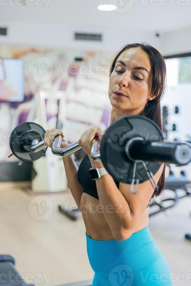 A woman is lifting weights in a gym, vertical photo with copy space