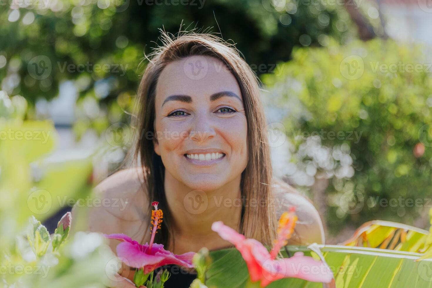 A woman is smiling and posing in front of a flower garden, happiness and carefree concept photo