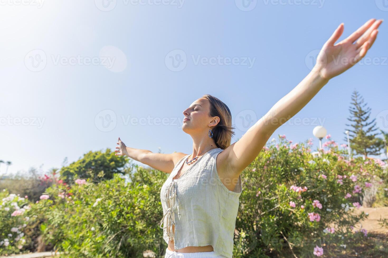 A woman is standing in a field of flowers, with her arms, Concept of peace and happiness. photo