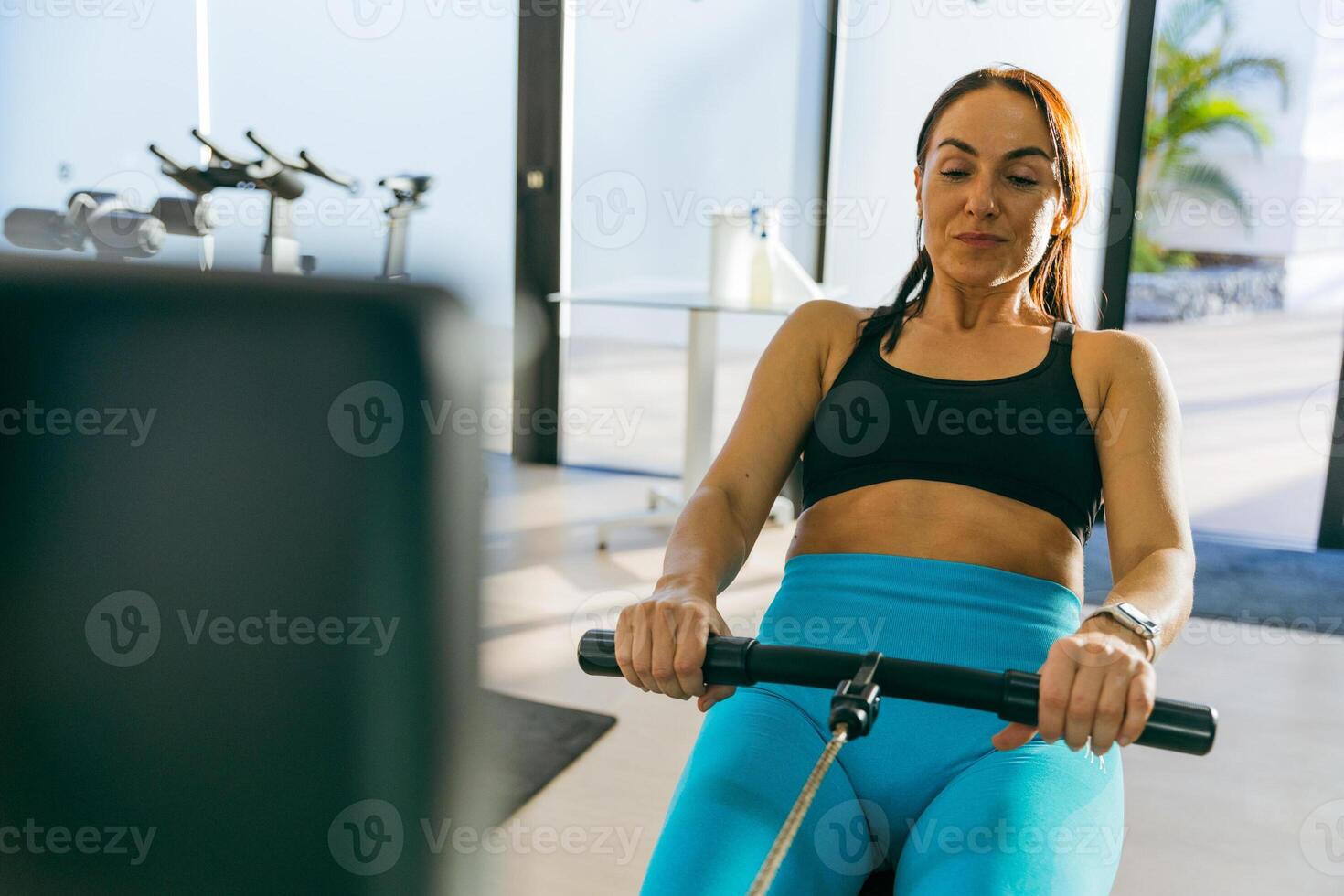A woman is rowing on a rowing machine in a gym photo