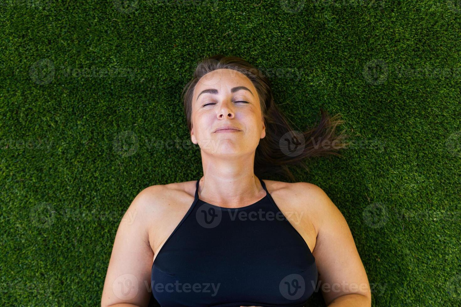 A woman is laying on the grass with her eyes closed and thinking, photo with copy space