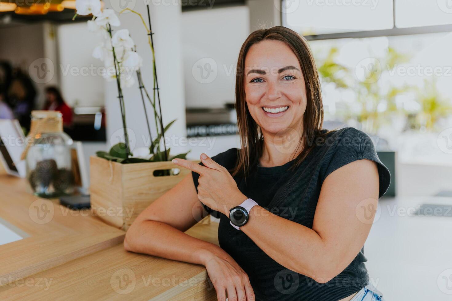 A smiling woman is smiling and pointing to the copy space on the left photo