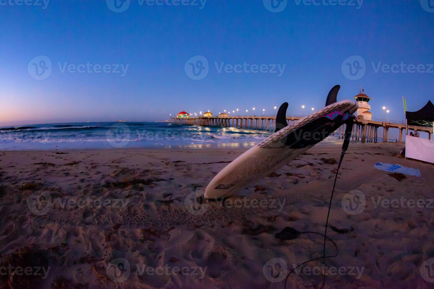 Dawn at the Huntington Beach Pier with a Surfboard in the Sand photo