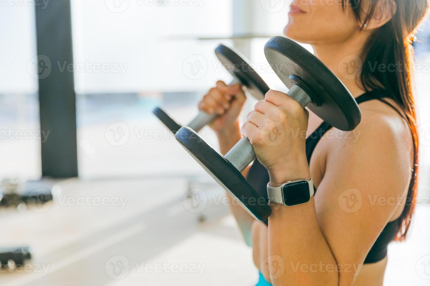 Close up of a woman's hands lifting dumbbells in a gym, photo with copy space