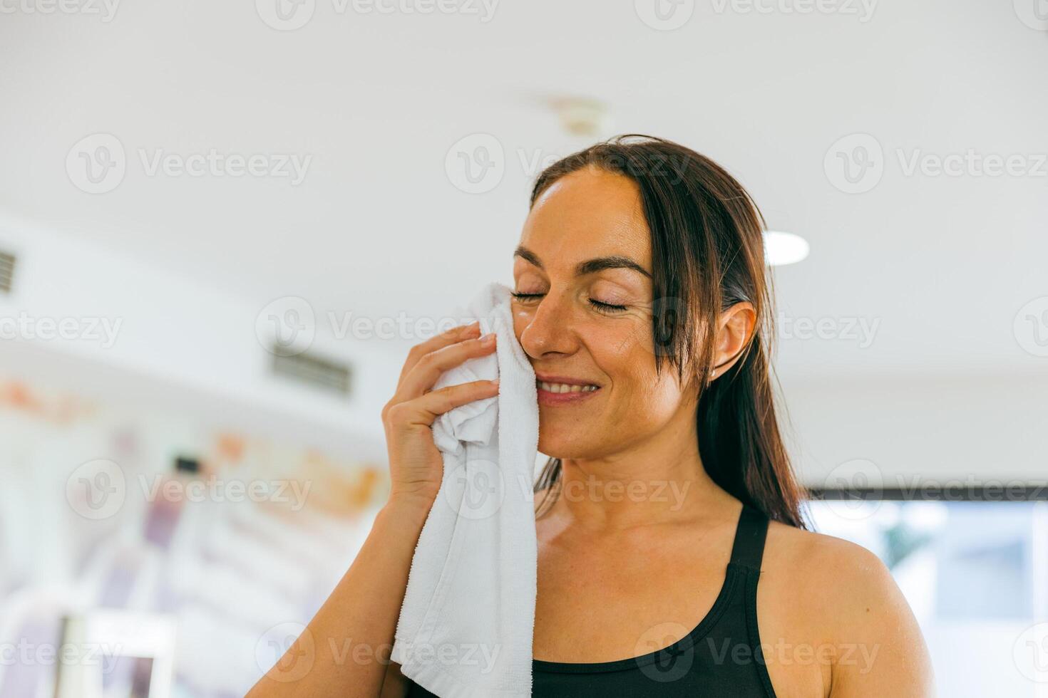 A smiling woman dries herself with a towel during training, photo with copy space