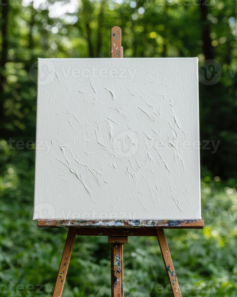 Blank white canvas on wooden easel in forest setting photo