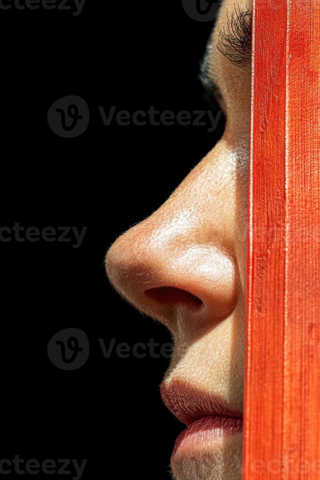 Close up profile of a womans face partially obscured by a red object photo