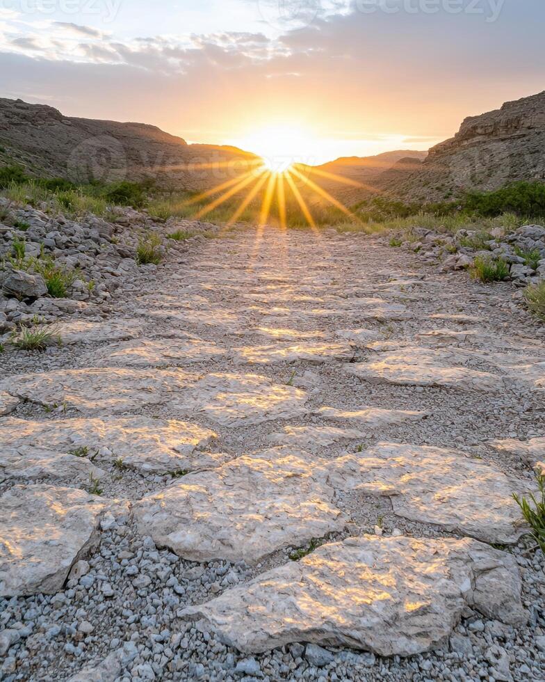 Sun rays bursting through a mountain pass illuminating a stone path photo