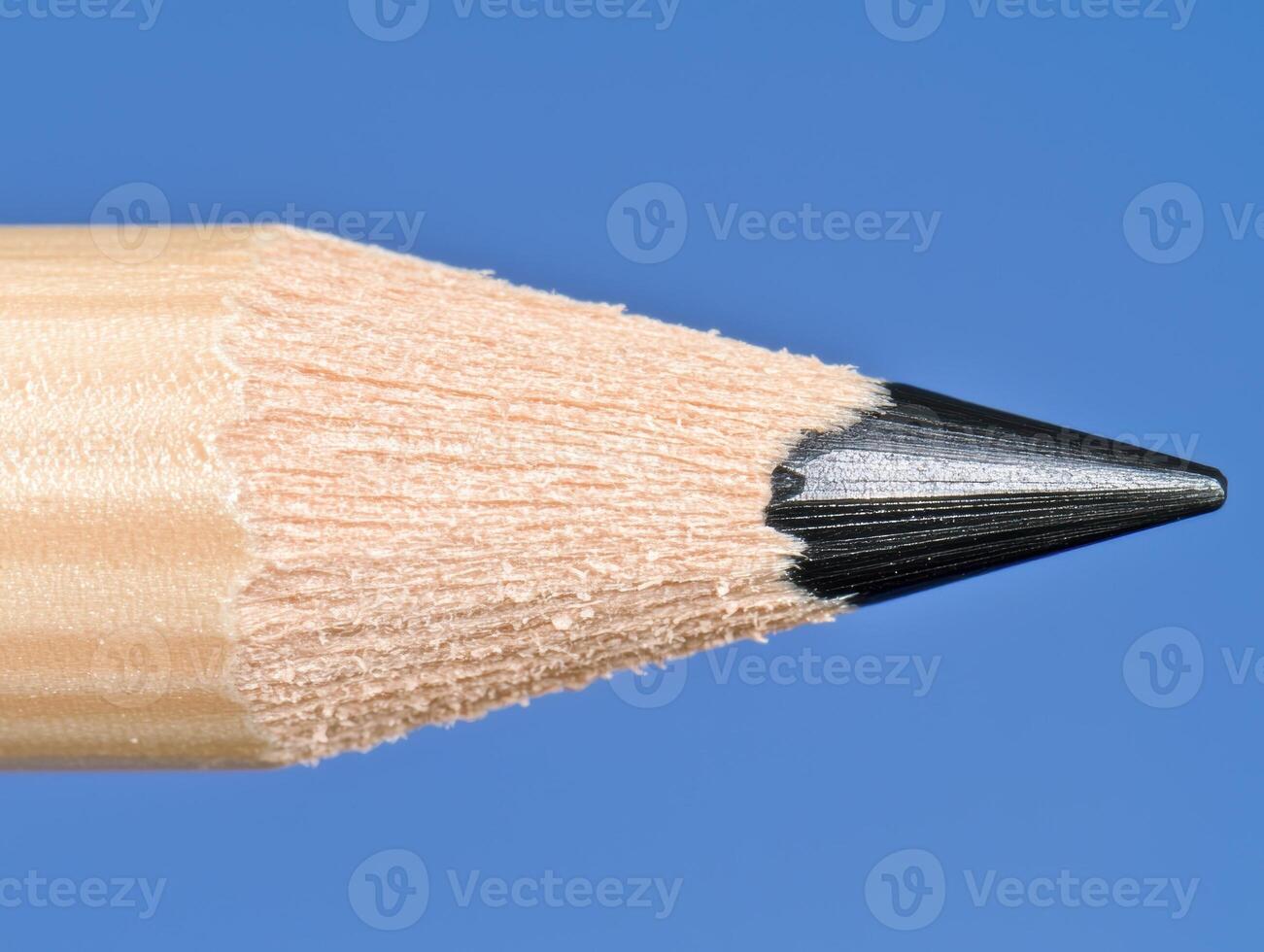 Close up of a sharpened pencil tip against a blue background photo