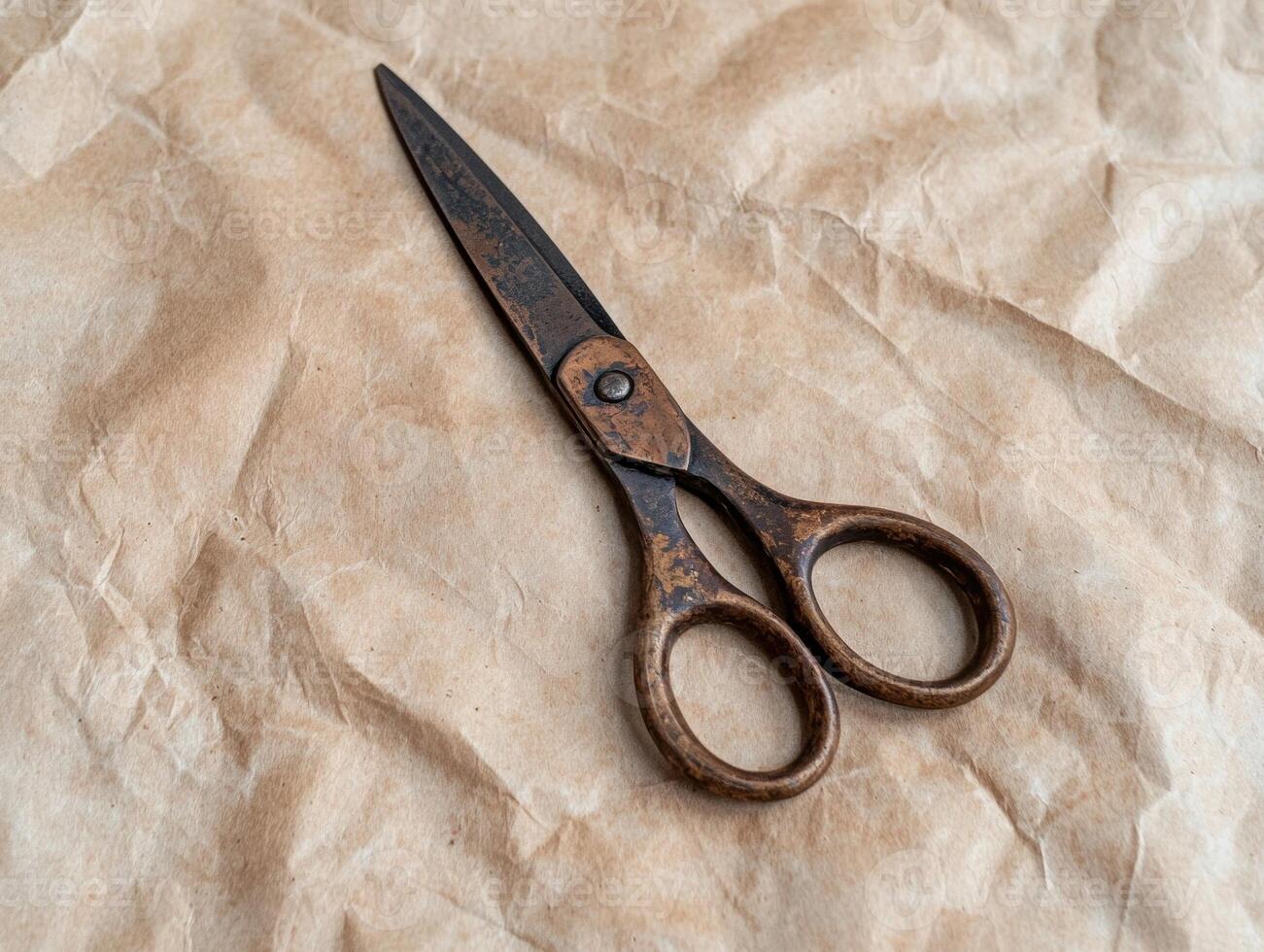 Antique rusty scissors on a crumpled brown paper surface photo