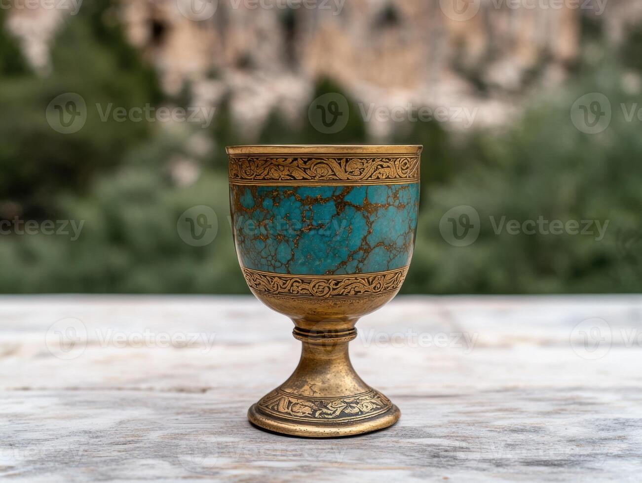 Ornate golden chalice with turquoise inlay on rustic wooden surface photo