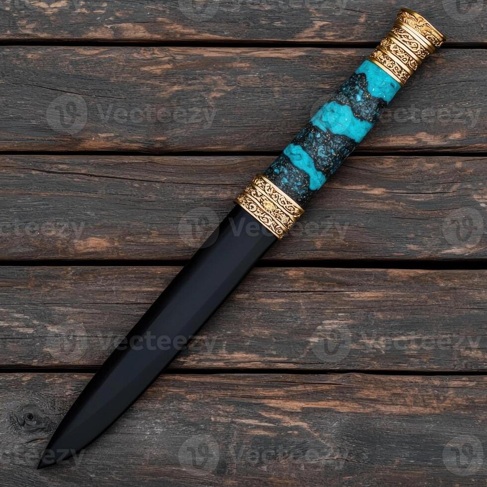 Ornate dagger with turquoise and gold handle on dark wood background photo