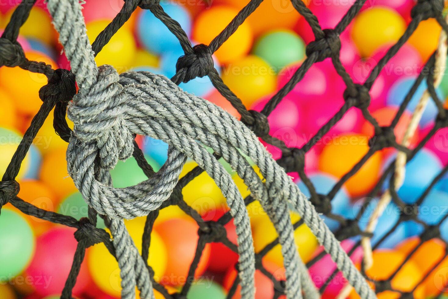 The net rope and colorful ball in children's playroom. Tight knot is used for safety barrier net. Children's playground photo