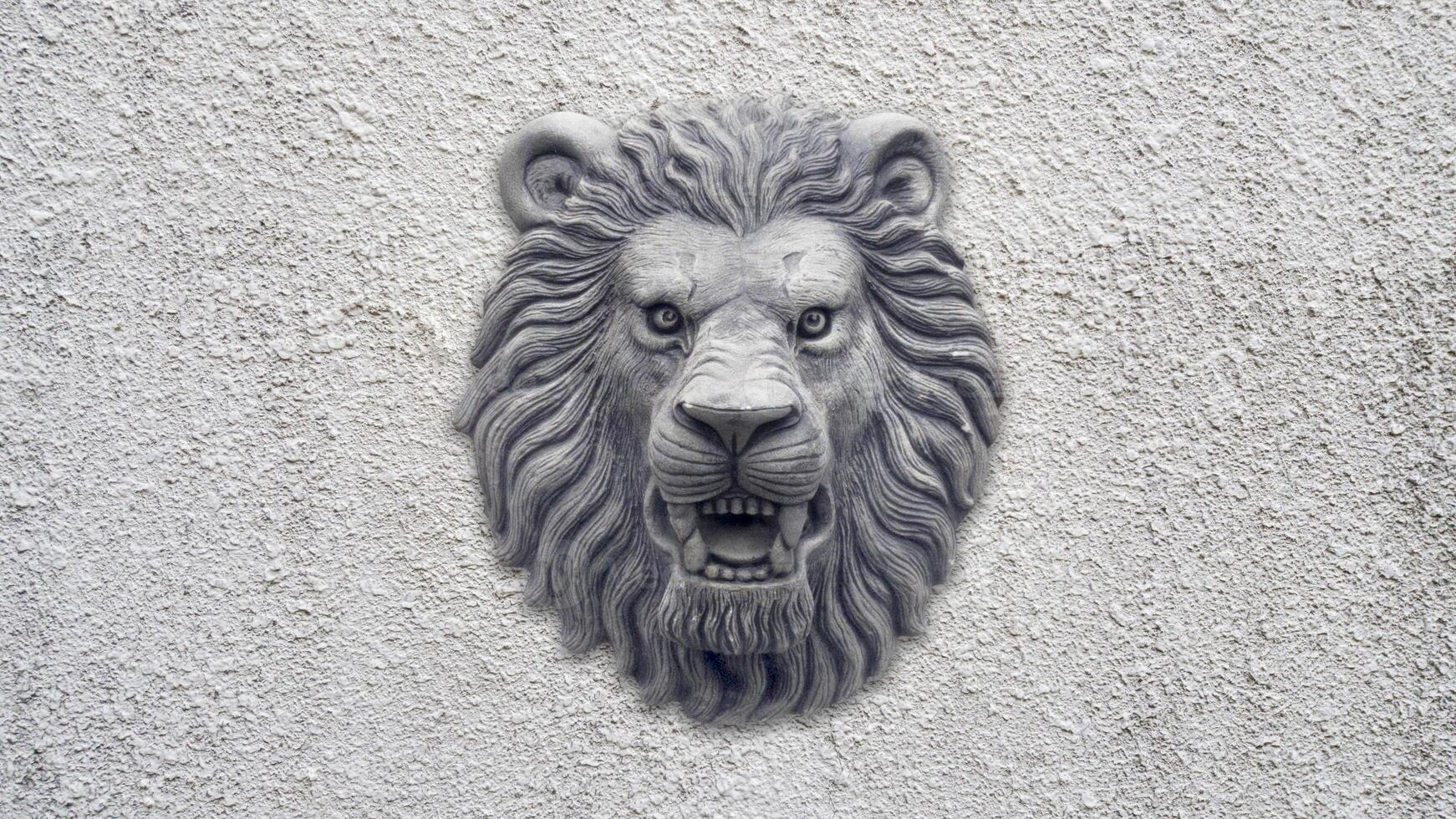 Grey Lion head statue on grey wall photo