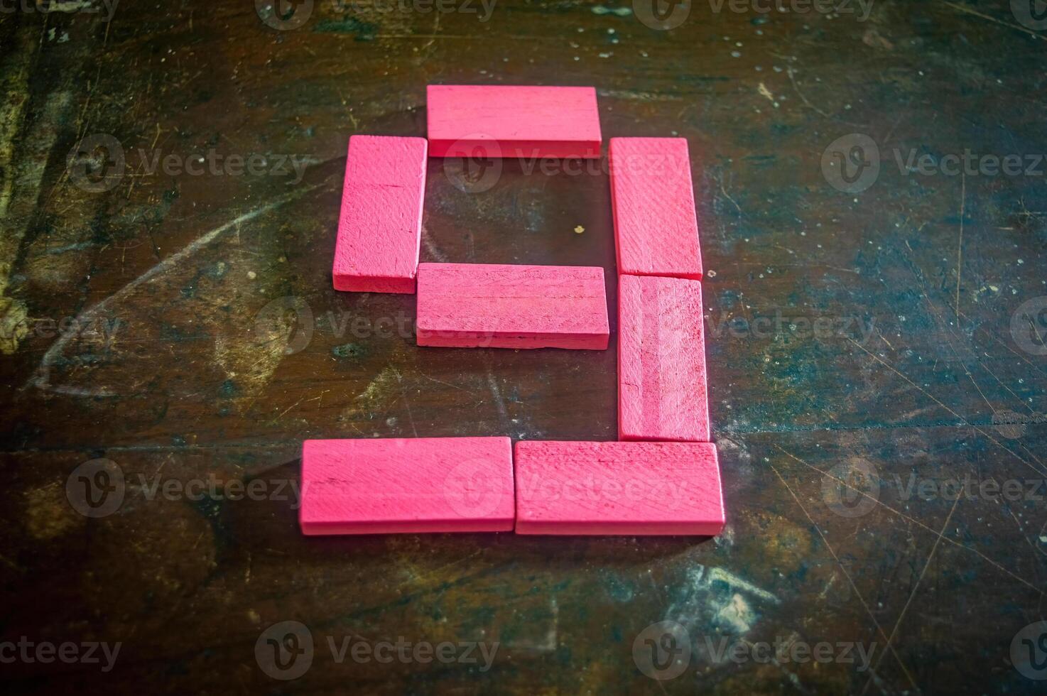 Red wooden blocks arranged in the shape of the number nine on a rustic wooden surface. Perfect for educational, numerical, or creative concepts photo