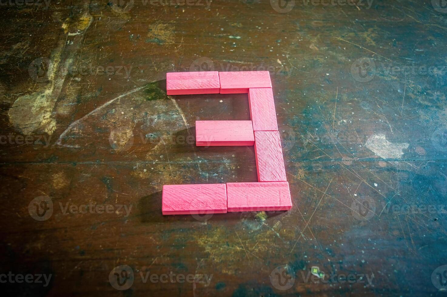 Red wooden blocks arranged in the shape of the number three on a rustic wooden surface. Perfect for educational, numerical, or creative concepts photo