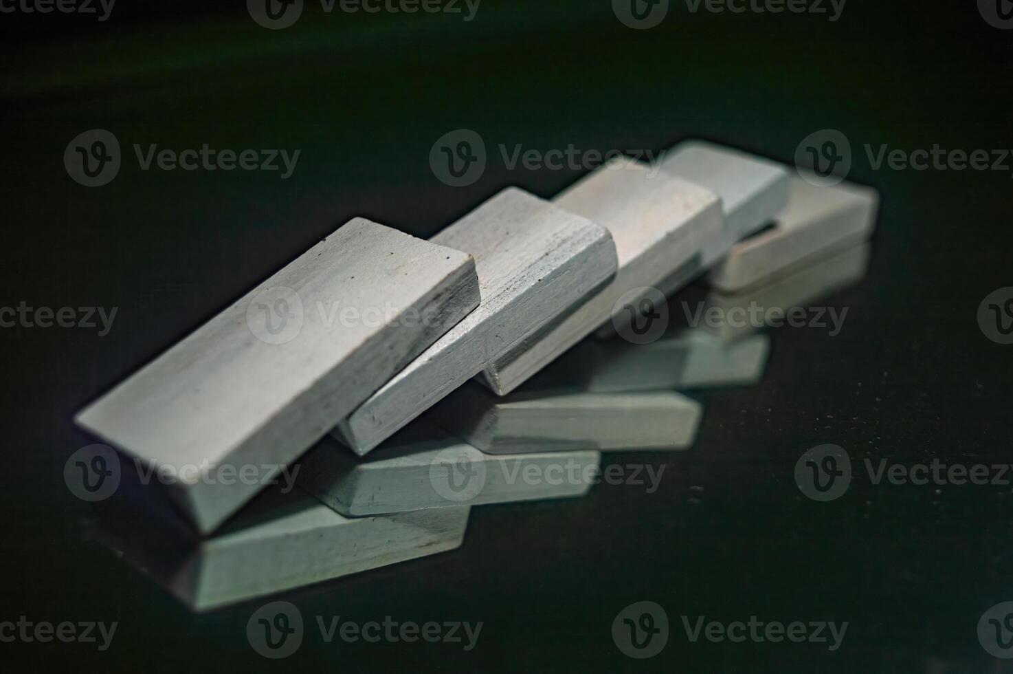 A close up image of five white rectangular blocks arranged in a domino effect on a reflective surface, creating an interesting visual pattern with their reflections photo