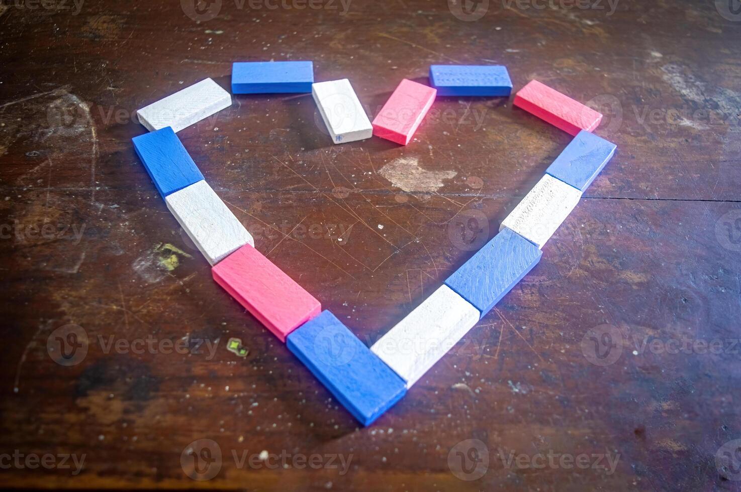 Colorful wooden blocks arranged in a heart shape on a rustic wooden table, creating a charming and playful design photo