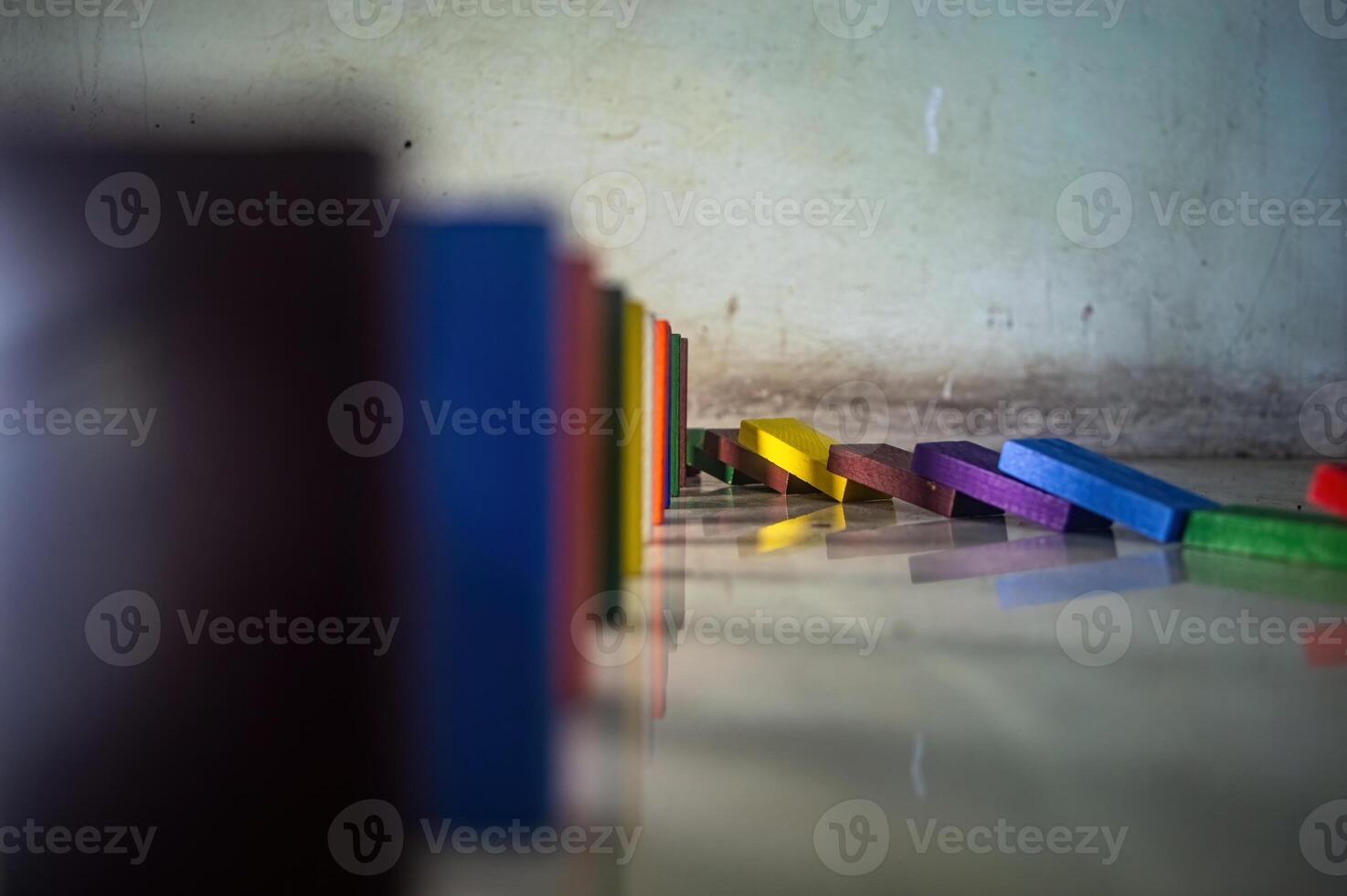Colorful wooden dominoes falling in a line on a white surface. Vibrant dominoes creating a colorful abstract pattern photo