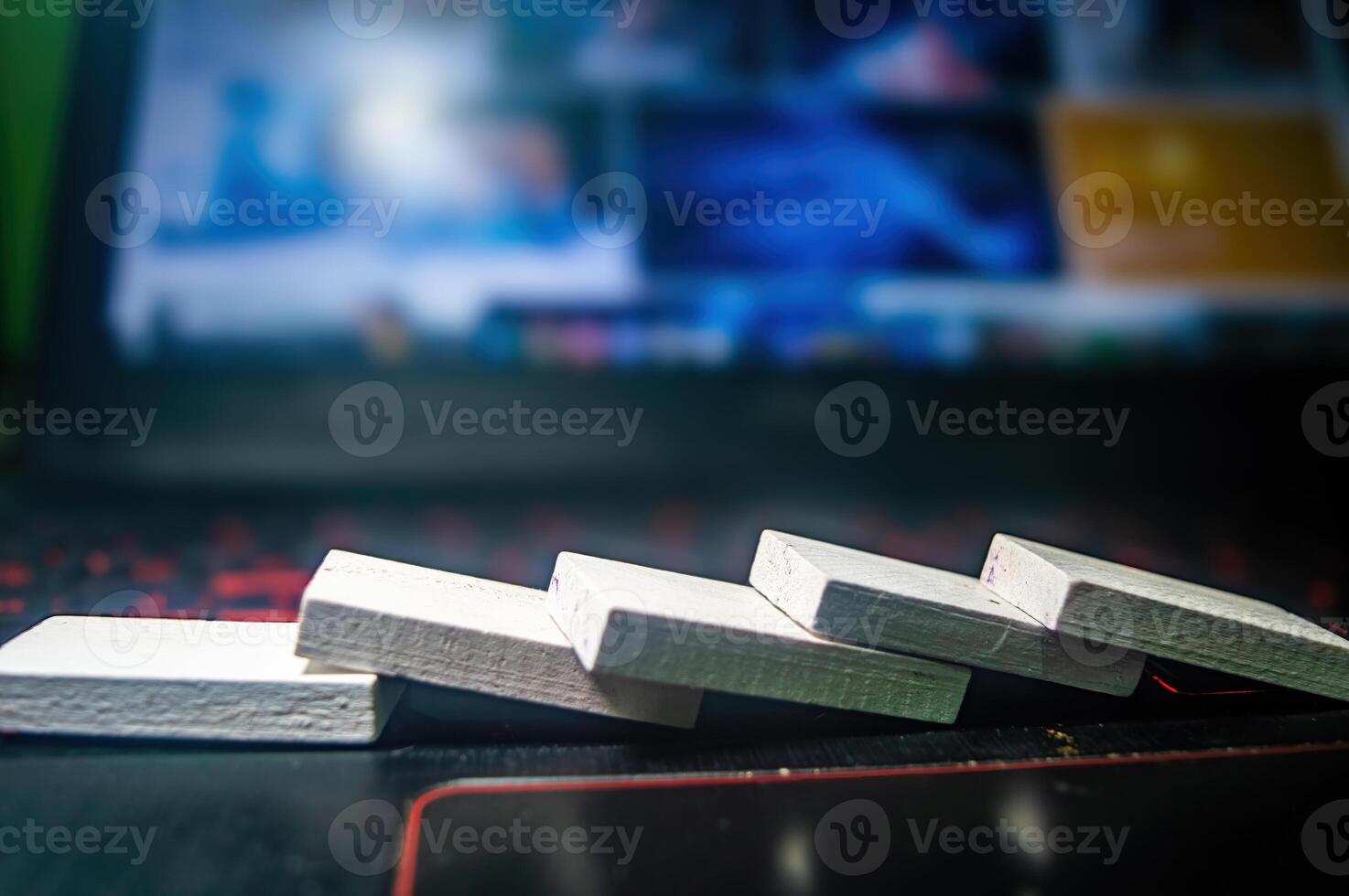 Close up of white wooden blocks falling in a domino effect on a laptop keyboard, symbolizing a chain reaction or cause and effect concept photo