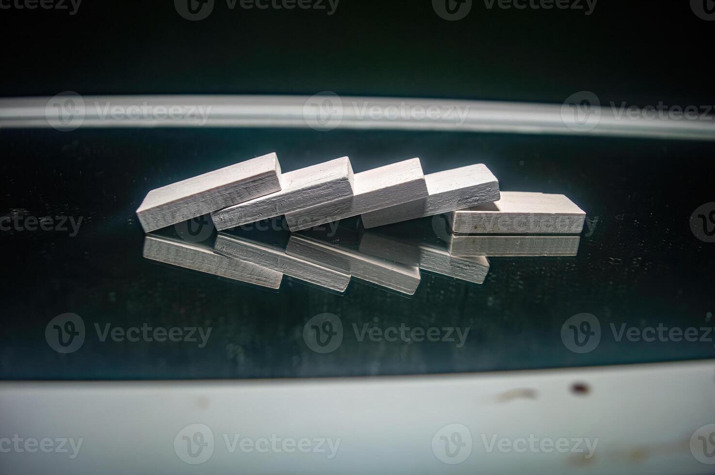 Wooden blocks arranged in a domino effect on a reflective surface, creating an interesting visual symmetry and balance photo